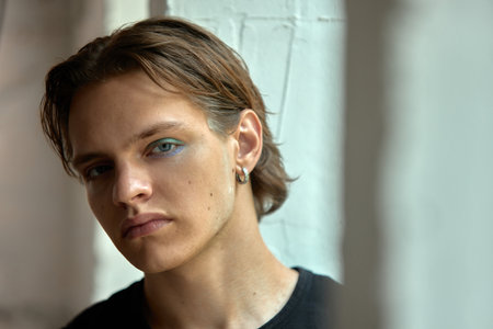 Bold dopamine. Man with gloss and icy-toned eyeshadow. Confident and bold. Concept of introspection and self-reflection in a modern space.の写真素材