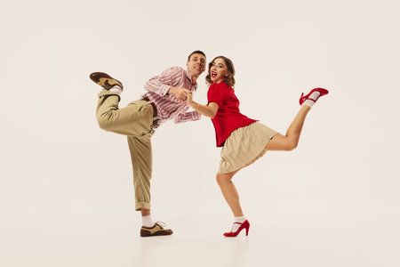 A retro couple joyfully performs energetic lindy hop dance moves on a plain white background. Concept of vintage dance enthusiasm and joy.の写真素材