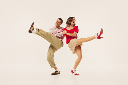 A couple in vintage attire energetically performs a lindy hop dance move. Concept of retro dance...