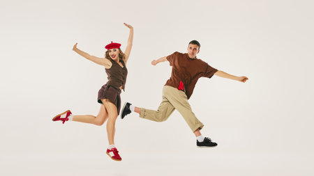 Energetic retro dancers perform a lindy hop routine, wearing vintage outfits, on a neutral background. Concept of classic dance revival in modern culture.の写真素材