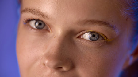 Closeup of a womans eyes with artistic makeup and a blue lighting background. Concept of creative beauty and artistic expression in modern makeup trends.の写真素材