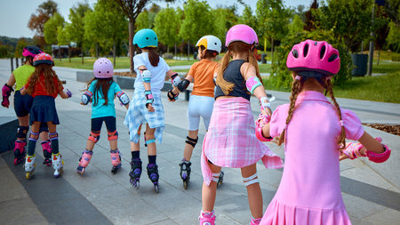 Children roller skate in a park wearing vibrant protective gear. Concept of active lifestyles for school-aged kids, diversity and inclusion in childhood activities, physical healthの写真素材