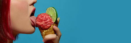 Woman licking meatball ice cream in cone with lime slice on turquoise background. Concept of surreal...