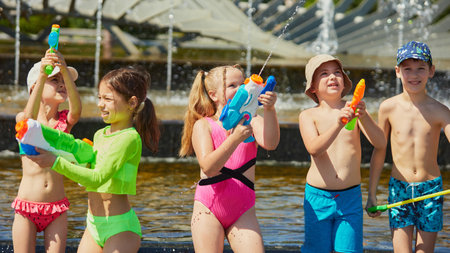 Children happily engage with aquatic toys in a sunny outdoor fountain space. Concept of inclusive summer fun promo, diverse childhood branding, emotional bonding across culturesの写真素材