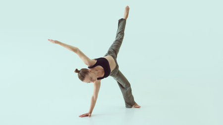 Female dancer holding one-arm floor balance with extended leg and intense focus. Concept of body...