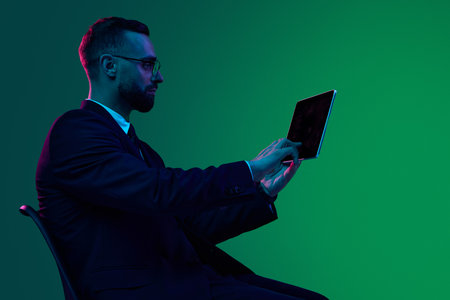 Businessman using tablet against vibrant green gradient background. Concept of cybersecurity awareness, mobile device identity protection, and tech brand visual storytelling.の写真素材