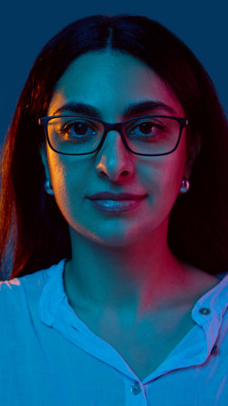 Woman in glasses with serious expression under colored lights. Concept of corporate branding,...