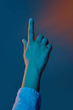 Hand pointing upward under dramatic blue and orange lighting. Concept of biometric access, secure interface design, digital banking UX, fintech verification.の写真素材