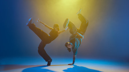 Male and female dancer striking synchronized acrobatic pose under stage lights. Concept of...