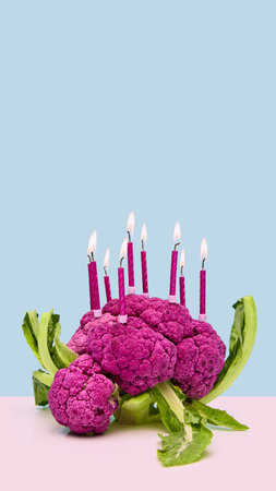 Purple cauliflower decorated with birthday candles on pastel background. Concept of creative food styling, plant-based celebration, healthy lifestyle, and sustainable party inspiration.の写真素材