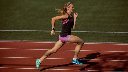 Athlete demonstrates exceptional speed and athletic prowess on an open-air track with powerful stride. Concept of sprint motion, speed training, dynamic strength, and explosive power in action.の写真素材