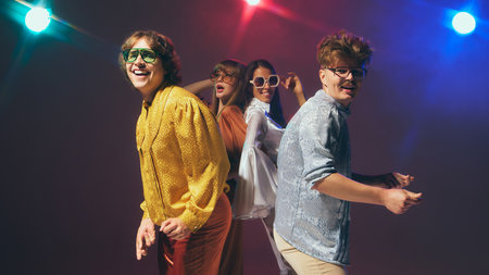 Four stylish friends laughing in vintage disco outfits. Concept of joyful retro lifestyle, nostalgic pop culture visuals.の写真素材