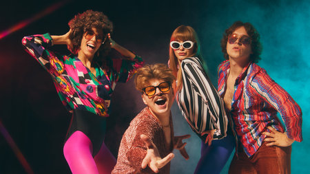 Glam retro group expressing charisma with colorful disco outfits. Concept of 70s inspired fashion, pop culture events, nostalgia lifestyle and vibrant party identityの写真素材