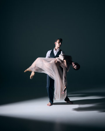 Ballet duet in dramatic floor carry with theatrical spotlight. Concept of editorial art, performance, romance, relationships, lifestyle, culture, spiritual depth and emotional storytelling.の写真素材