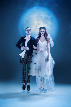 Gothic groom carrying eerie bride in fantasy moonlight scene. Concept of spooky romance, avant-garde...