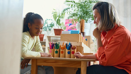 Teacher guiding child in creative classroom activity for psychological support. Concept of child...