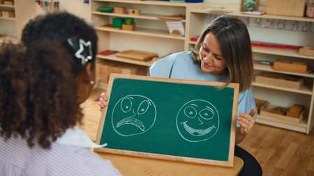 Teacher showing chalkboard with emotional drawings to child during counseling session. Concept of psychology therapy, education, pediatric healthcare, social media campaigns.の写真素材