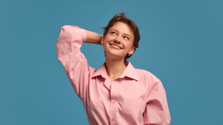 Smiling woman touching head with dreamy thoughtful expression. Concept of daydreaming, creativity, and emotional awareness for psychology, education, and lifestyle content.の写真素材