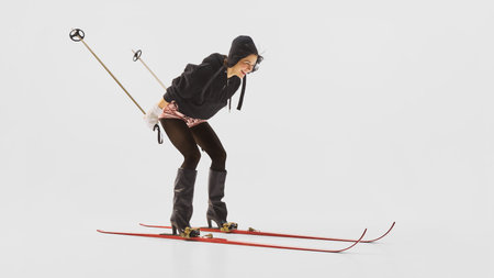 Smiling woman skiing in black outfit and pink shorts in studio setting. Concept of joyful winter fashion, elegance, and confidence for influencer lifestyle, branding, and editorial design.の写真素材
