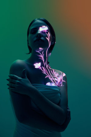 Woman with glowing floral projection on face and chest in dark gradient lighting. Concept of human nature harmony, emotion, creativity for fashion, editorial, and wellness communication visuals.の写真素材