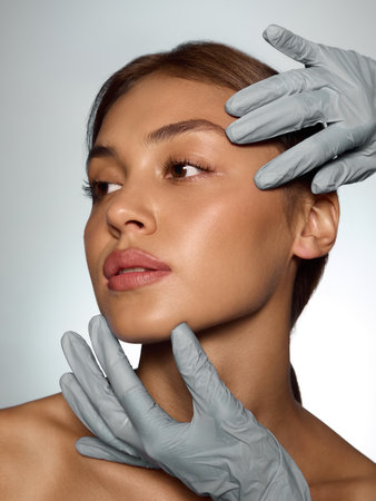 Doctor hands in gloves examining woman face with precision and patient confidence. Concept of...