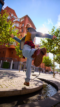 Energetic man in denim jacket kicking foot in sunlight showing urban confidence. Concept of travel freedom, urban lifestyle, and expressive fashion culture inspired by movement and joy.の写真素材