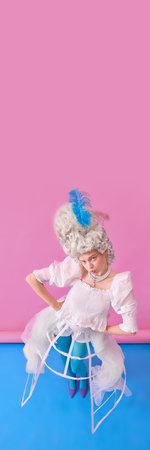 Young woman as Marie Antoinette standing in corset and bright tights with hands on hips. Concept of...