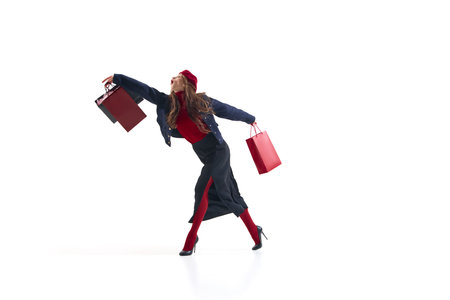 Fashion woman in red and navy outfit walking gracefully with shopping bags in motion. Concept of elegant lifestyle, retail energy, modern fashion expression for editorial and advertising use.の写真素材