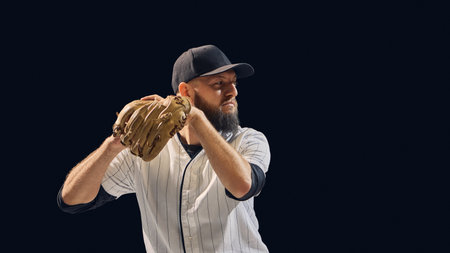 Baseball pitcher holding ball and glove in ready position on dark background. Concept of pitching preparation, focus, and technical training for coaching and sports visuals.の写真素材