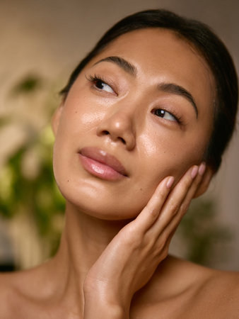 Woman touching hydrated skin with soft calm expression. Concept of body confidence, health awareness, and mindful connection between beauty and wellbeing.の写真素材