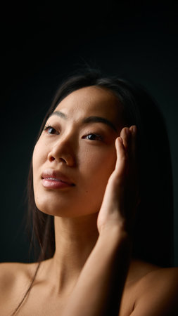 Woman touching temple with calm expression and balanced natural beauty. Concept of stress relief, mindfulness, skincare awareness, and emotional stability in personal wellness.の写真素材