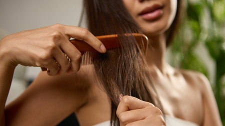 Close view of woman combing hair showing strength softness and health. Concept of daily hair care, beauty maintenance, and relaxation through mindful personal grooming.の写真素材
