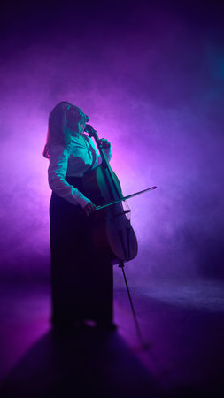 Cellist performing with concentration under magenta light and smoke. Concept of lifestyle and editorial photography, and art design production.の写真素材