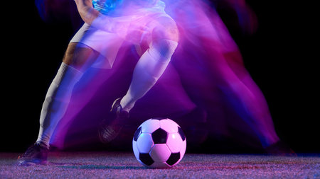 Soccer player dribbling ball in motion blur under violet neon lights. Concept of control, creativity, and focus in sport education, teamwork, and commercial athletic advertising.の写真素材