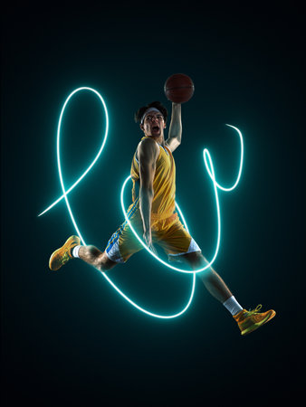 Basketball player dunking with bright neon light streaks showing intensity. Concept of athletic poster visuals and performance-driven campaigns.の写真素材