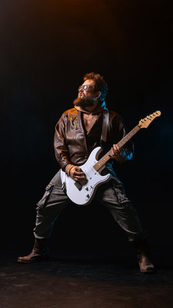 Rock guitarist performing in strong pose with electric guitar and confidence. Concept of creative power, motivation, music posters, emotional energy, and individuality in stage performance.の写真素材