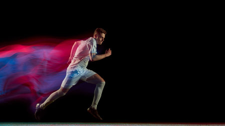 Football player running fast with glowing red and blue motion blur in dynamic action. Concept of...