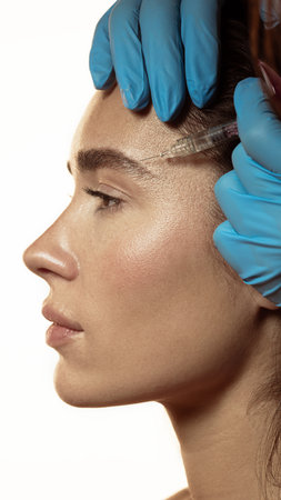 Dermatologist performing temple area injection with precision and control. Concept of calm professionalism, rejuvenation, and harmony in aesthetic facial medicine.の写真素材