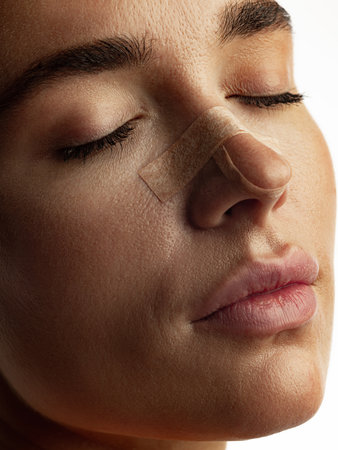 Woman resting peacefully with nose bandage after beauty correction recovery phase. Concept of...