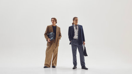 Two stylish male professionals posing confidently in modern tailored office outfits. Concept of...