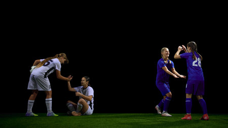 Female soccer players helping teammate after fall during match. Concept of fair play lessons, sports ethics materials, social values education, teamwork campaigns.の写真素材