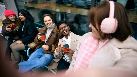 Group selfie moment of cheerful winter friends near storefront. Concept of social media visuals, lifestyle promotion, cafe-centric event communication, and warm emotional tone.の写真素材