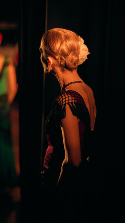 Ballet dancer waiting between curtains under directional stage light. Concept of entry positioning, timing control and situational awareness within structured stage-access routines.の写真素材