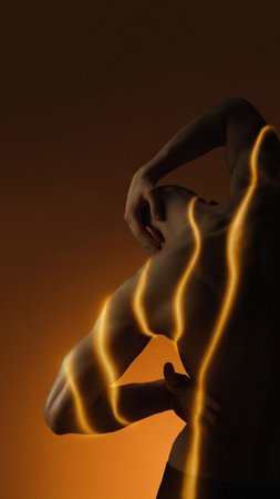 Digital composition of male back wrapped in warm orange energy lines. Concept of back care, muscle...