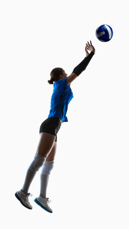 Female teenage volleyball athlete jumping upward with arms extended toward ball. Concept of tactical diagrams, vertical jump analysis, coaching lessons.の写真素材
