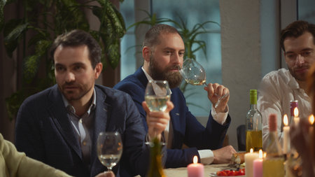 Men sitting together at dinner table in relaxed atmosphere. Concept of male lifestyle content, wine...