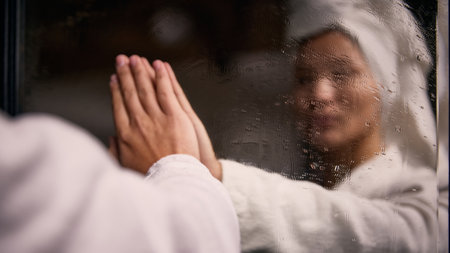 Woman touching foggy mirror after shower in bathroom. Concept of intimate self care, wellness atmosphere, skincare lifestyle, emotional reflection and calm solitude.の写真素材
