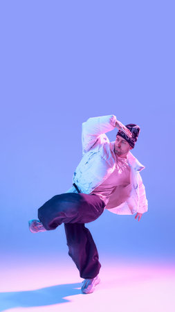 Male street dancer posing with raised arm in neon studio lighting. Concept of contemporary dance...