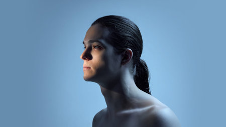 Male portrait in blue cinematic light with serious expression. Concept of emotional health visuals, aesthetic medicine campaigns, psychological depth communication, and contemporary art assets.の写真素材