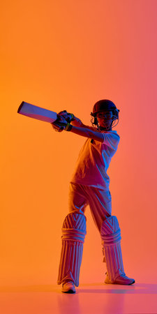 Young cricket player holding bat extended forward under neon orange lighting. Concept of sports ads...